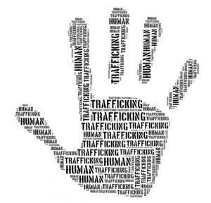 The image displays a word cloud shaped like a hand, composed of repeated phrases "Human Trafficking," highlighting the issue of human trafficking.