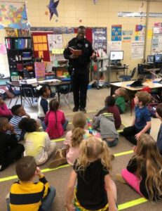 School Resource Officer is doing a presentation in a classroom of elementary aged school children.