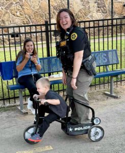 Photo of Deputy Taylor Sullivan pictured with a friend eating ice cream and a young child riding a toy