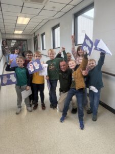 Nick Dean is surrounded by elementary students holding up their artwork